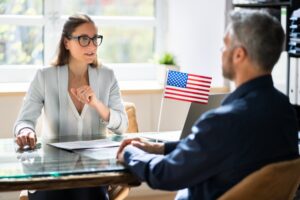 Man and woman sitting at a desk with an American flag on the table