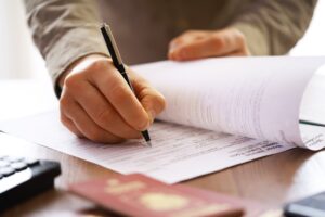 Person holding a pen filling out paperwork at a desk