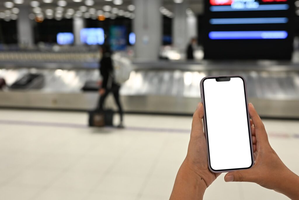 Someone at the airport on their phone by baggage carousel