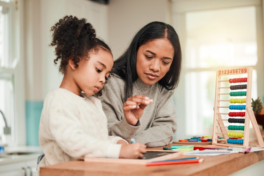 A woman and a child sitting at a table with colored pencils and paper drawing