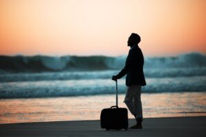 Sunset, beach and a man with a suitcase