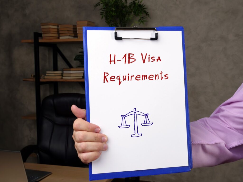 Person holding a clipboard with the words 'H-1B Visa Requirements' and a picture of a scale