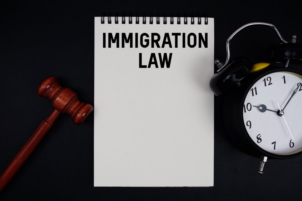 A gavel next to a notebook that says immigration law next to a clock