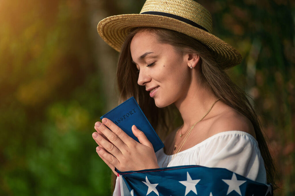 Woman Holds American Flag & Passport | Labor Certification Services | U.S. Immigration Law Counsel