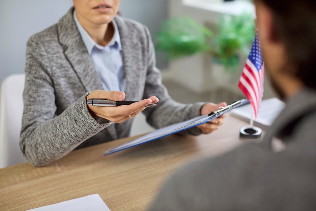 Zoomed in picture of two people sitting across each other at a table with a US flag on the table