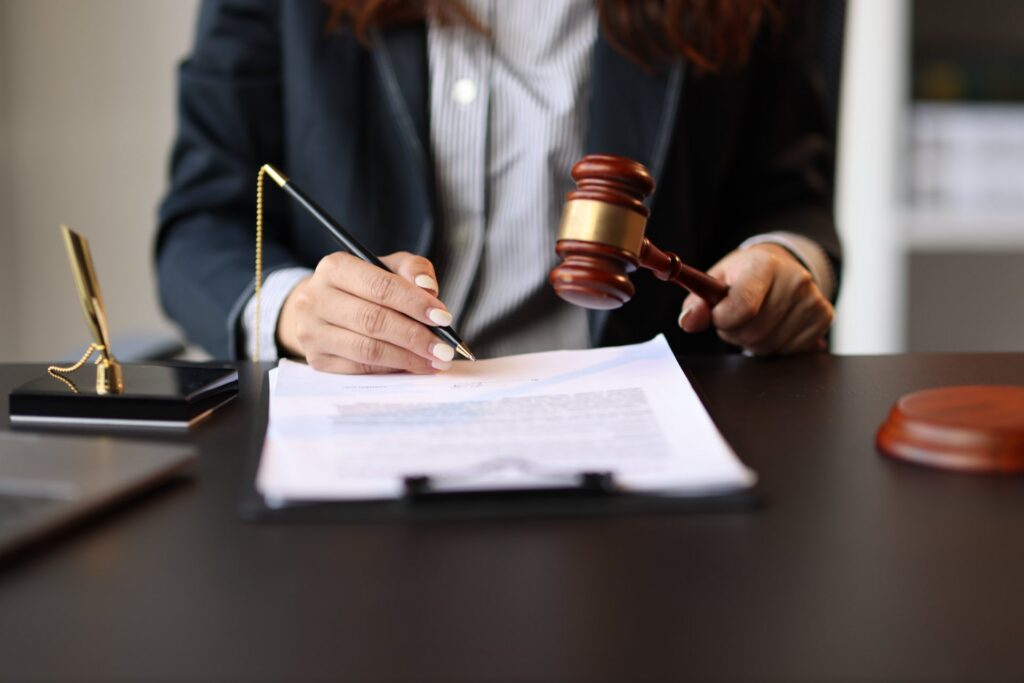 Woman sitting at a desk holding a pen in one hand and a gavel in the other