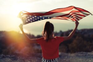 Woman holding american flag with a desert as the background
