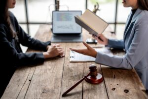 Two people sitting at a desk going over paperwork with a gavel next to them