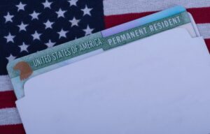 Close up view of an envelope with a permanent resident card in it with a flag as the background