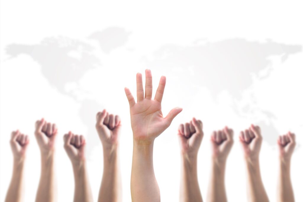 9 hands in the air 8 of them have fists closed and one hand is open with a white background