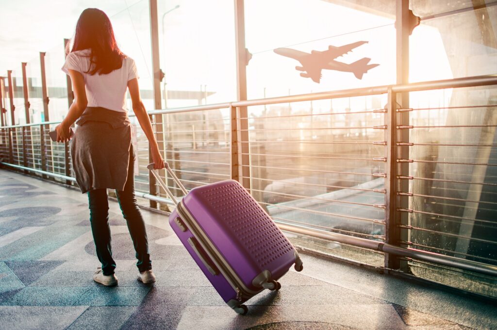 Woman Pulling Suitcase in Airport | Experienced Student Visa Lawyers | U.S. Immigration Law Counsel