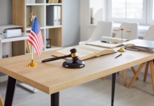 A desk with a gavel, flag, book and paper work on it
