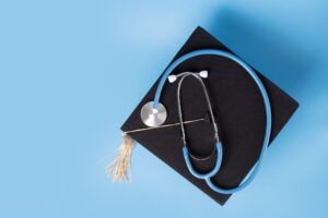 Stethoscope on top of a graduation cap with a blue background