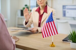 Zoomed in picture of two people sitting at a desk next to an American flag