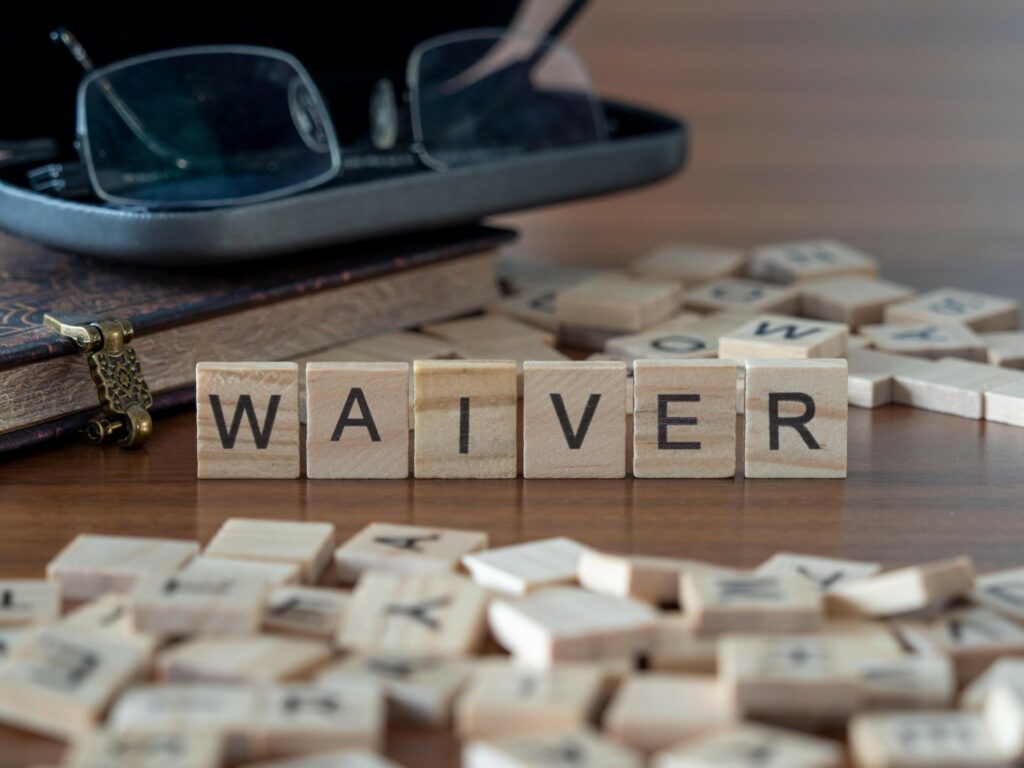 Wooden letters saying waiver with glasses in the background