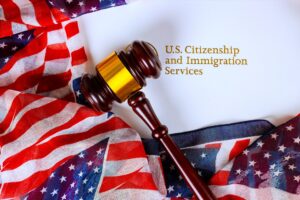 A gavel on top of an envelope that says U.S. Citizenship and Immigration Services on top of an American flag